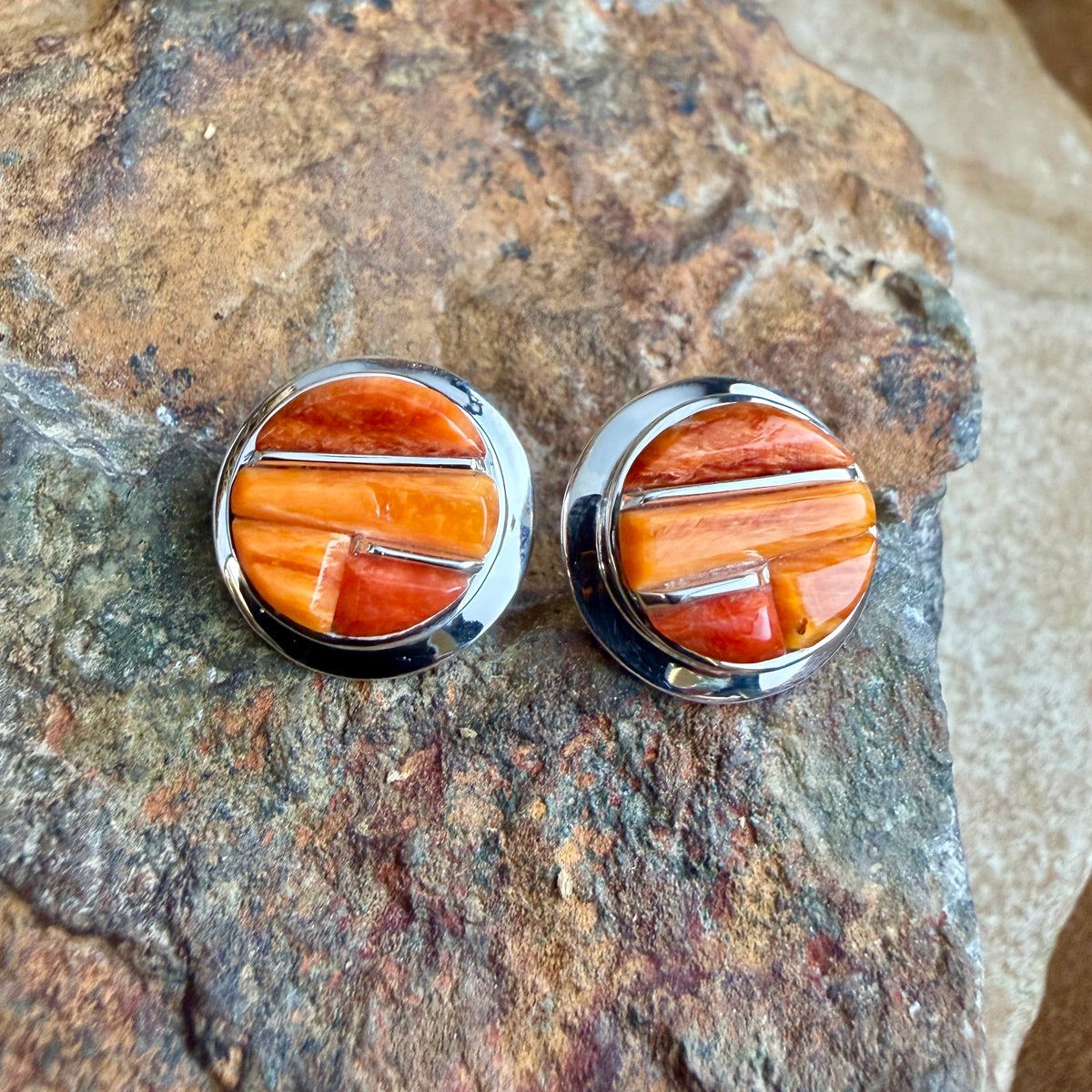 Spiny Oyster shell cobble inlay and sterling post earrings on a rock surface. 
