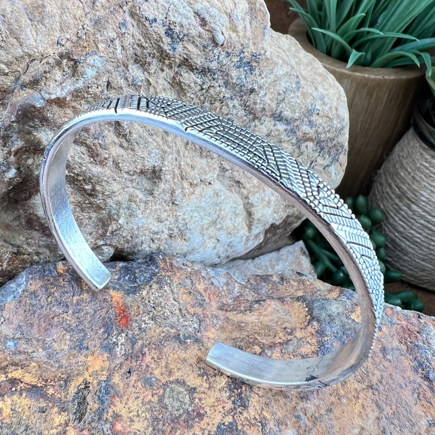 Silver bracelet with textured design on a rock surface