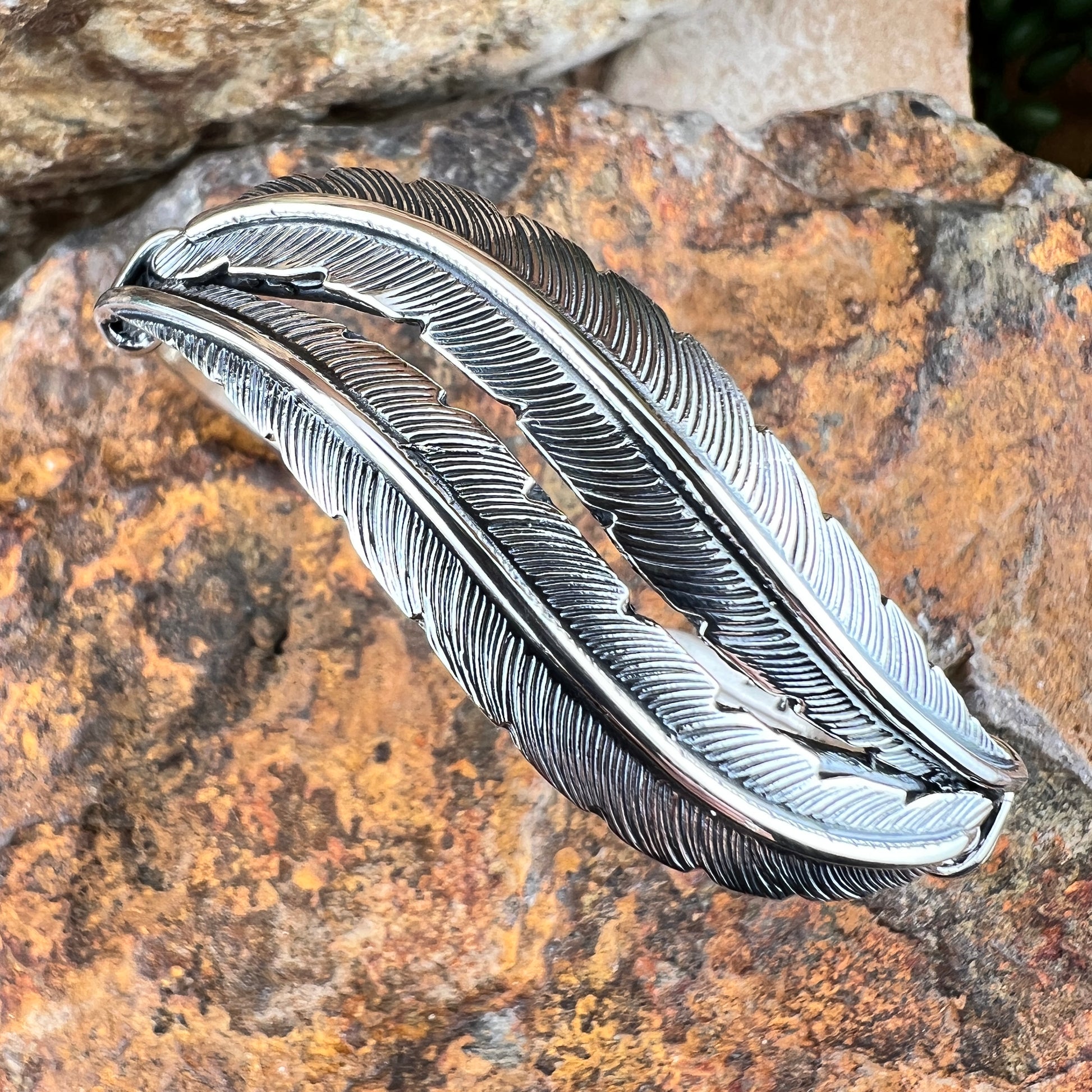 Silver feather-shaped object on a textured stone surface