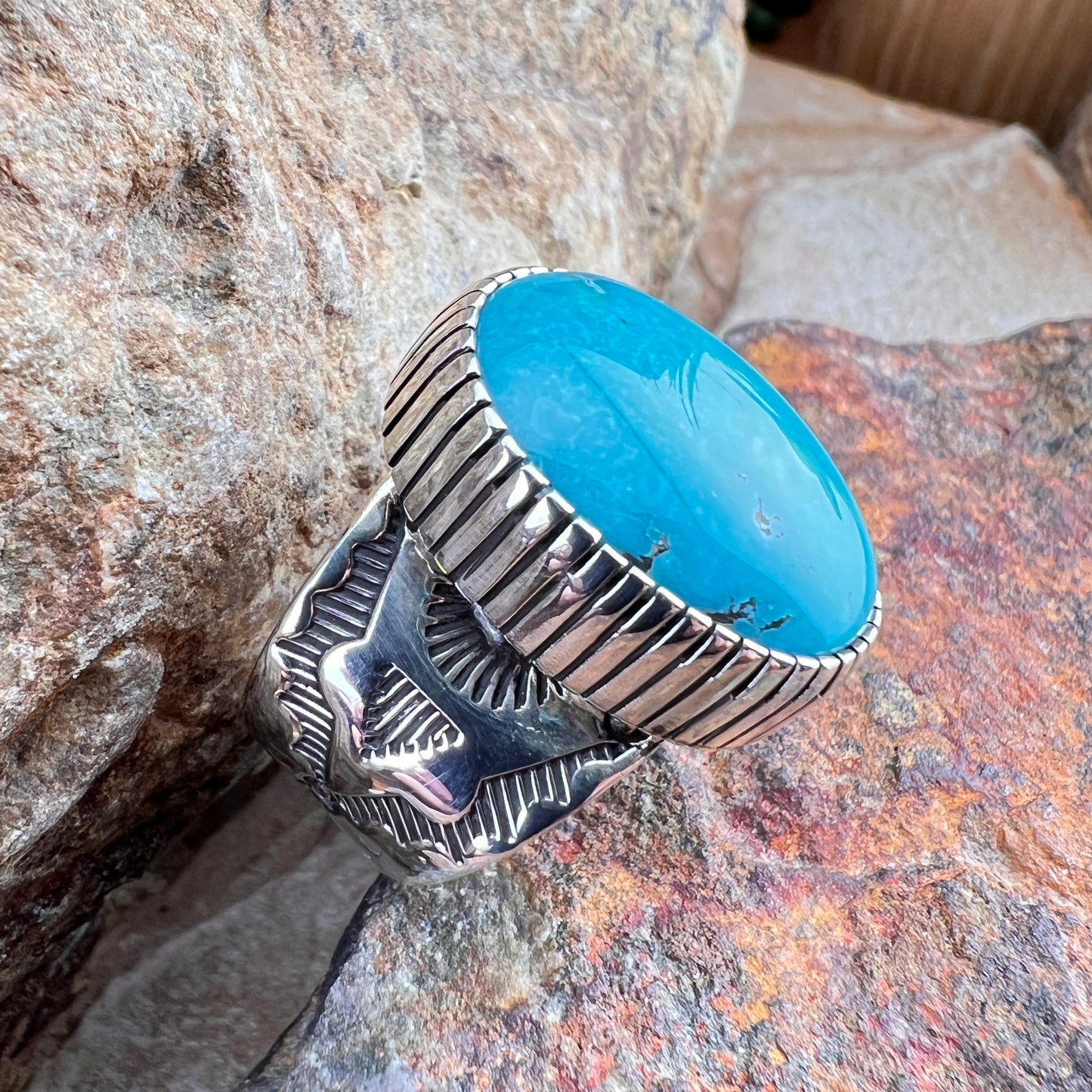 Silver ring with a blue stone on a stone surface