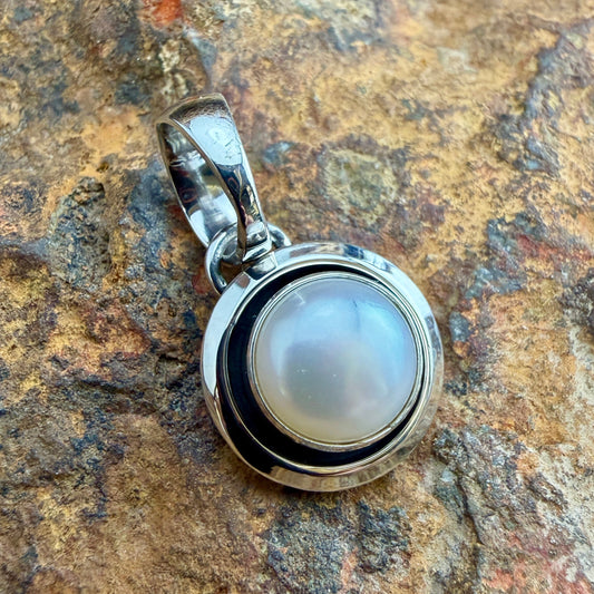 Sterling Silver Freshwater Pearl Pendant by Artie Yellowhorse - angled front view showing round pearl in polished shadowbox setting
