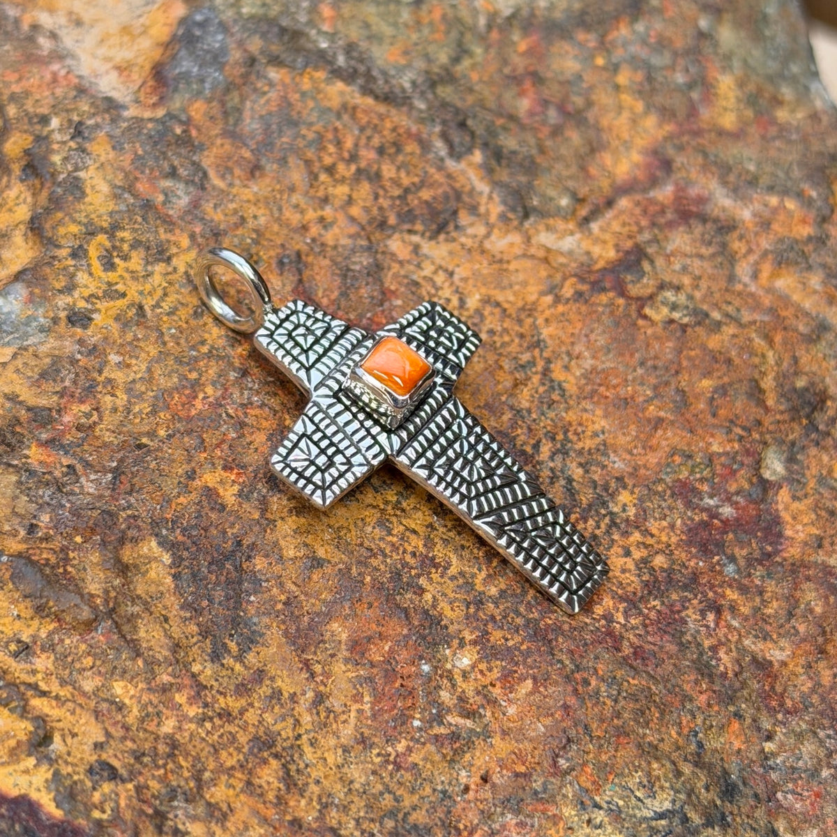 Orange spiny oyster shell cross pendant by Elgin Tom, angled view