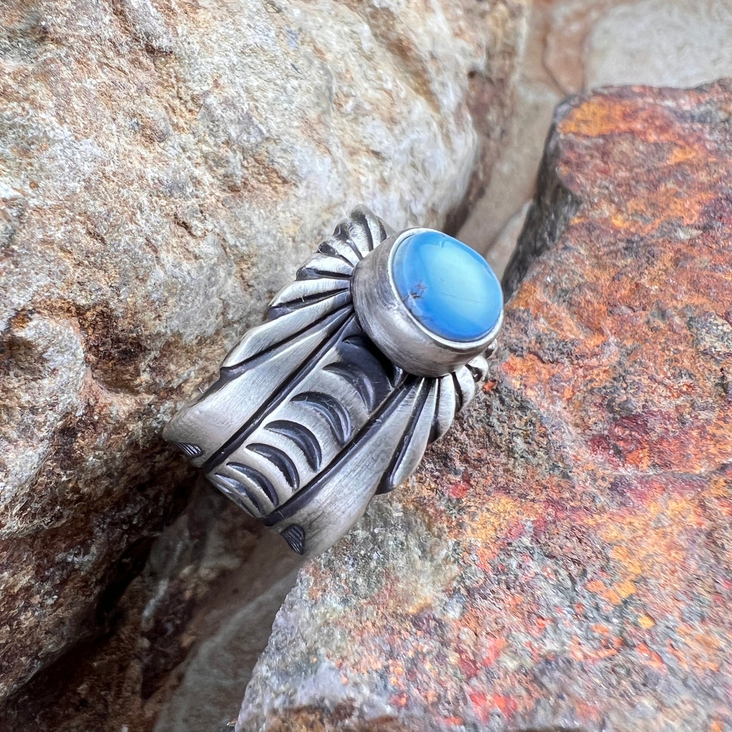 Silver ring with a blue stone embedded in a rocky surface