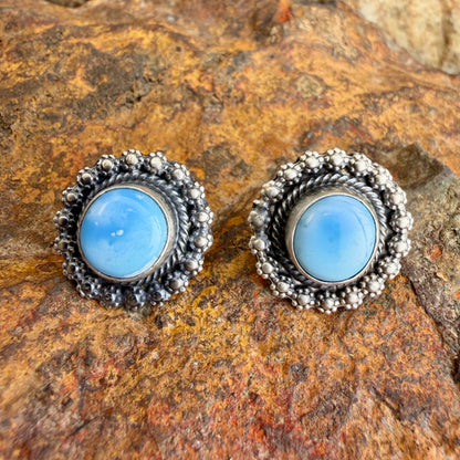 Pair of silver earrings with blue gemstones on a stone surface