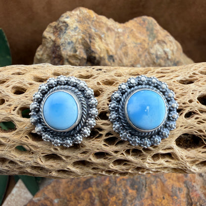 Pair of silver earrings with blue stones on a textured surface