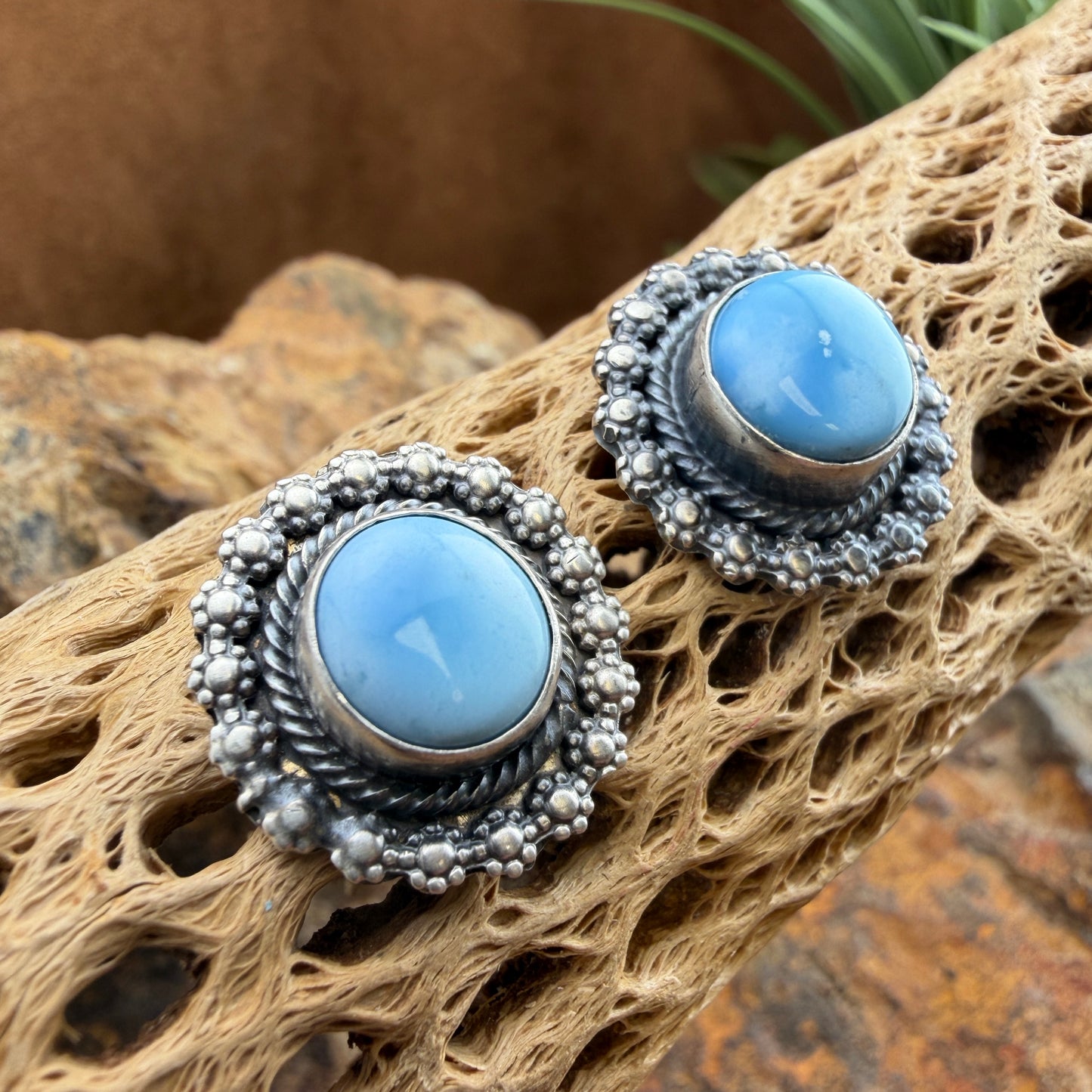 Pair of silver earrings with blue stones on a textured brown surface
