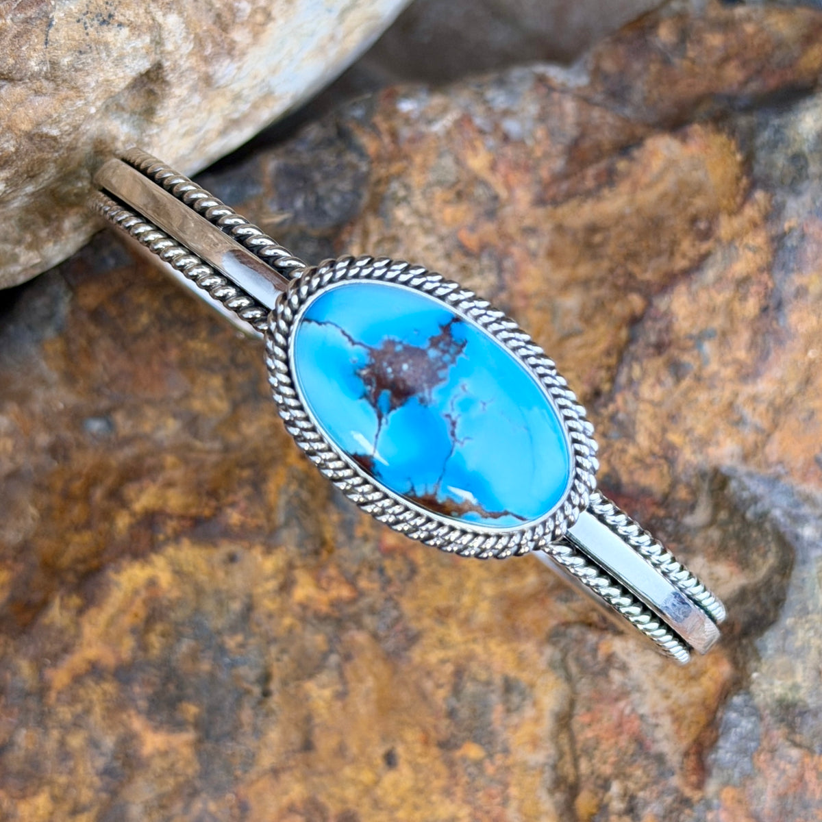 Angled view of sky-blue Golden Hills turquoise oval cuff with natural brown matrix and twisted-rope sterling silver border