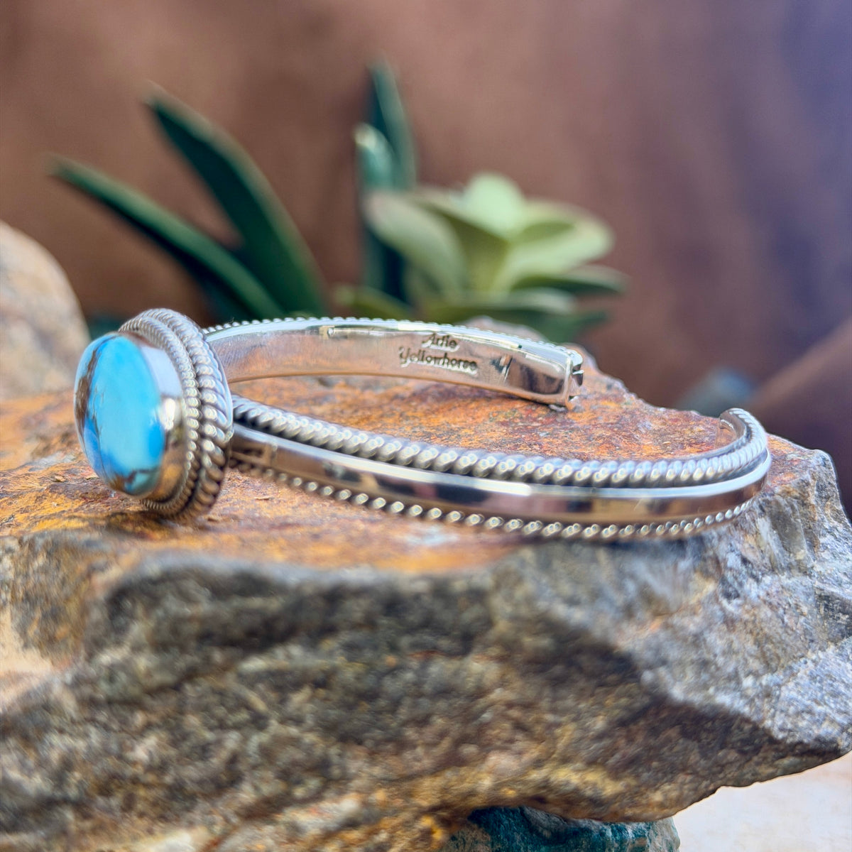Side view of open cuff with polished silver rails and twisted-rope trim