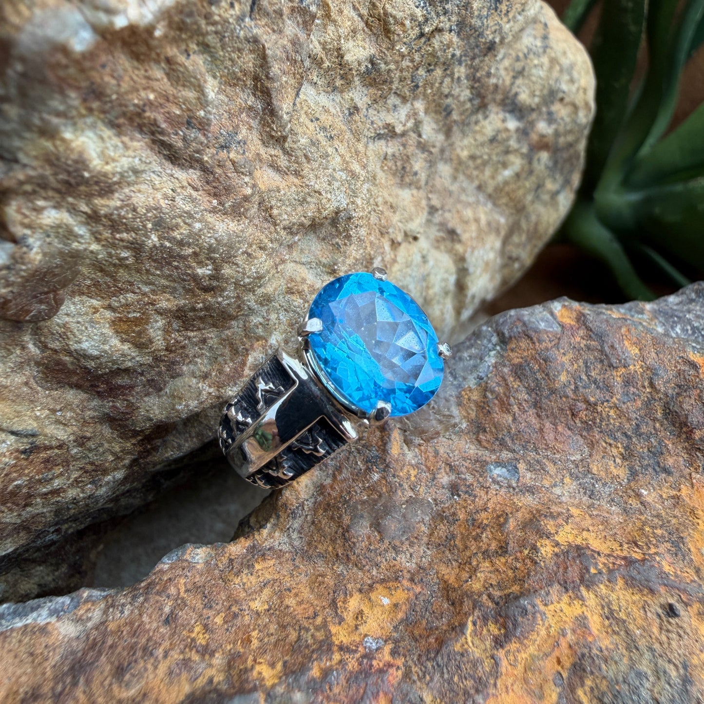 Ring with a blue gemstone and silver band on a textured stone surface