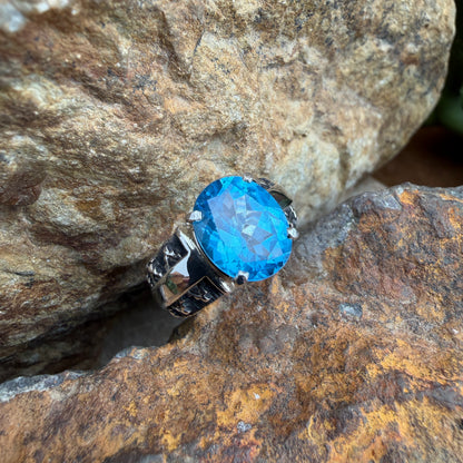 Ring with a blue gemstone and silver band on a textured stone surface