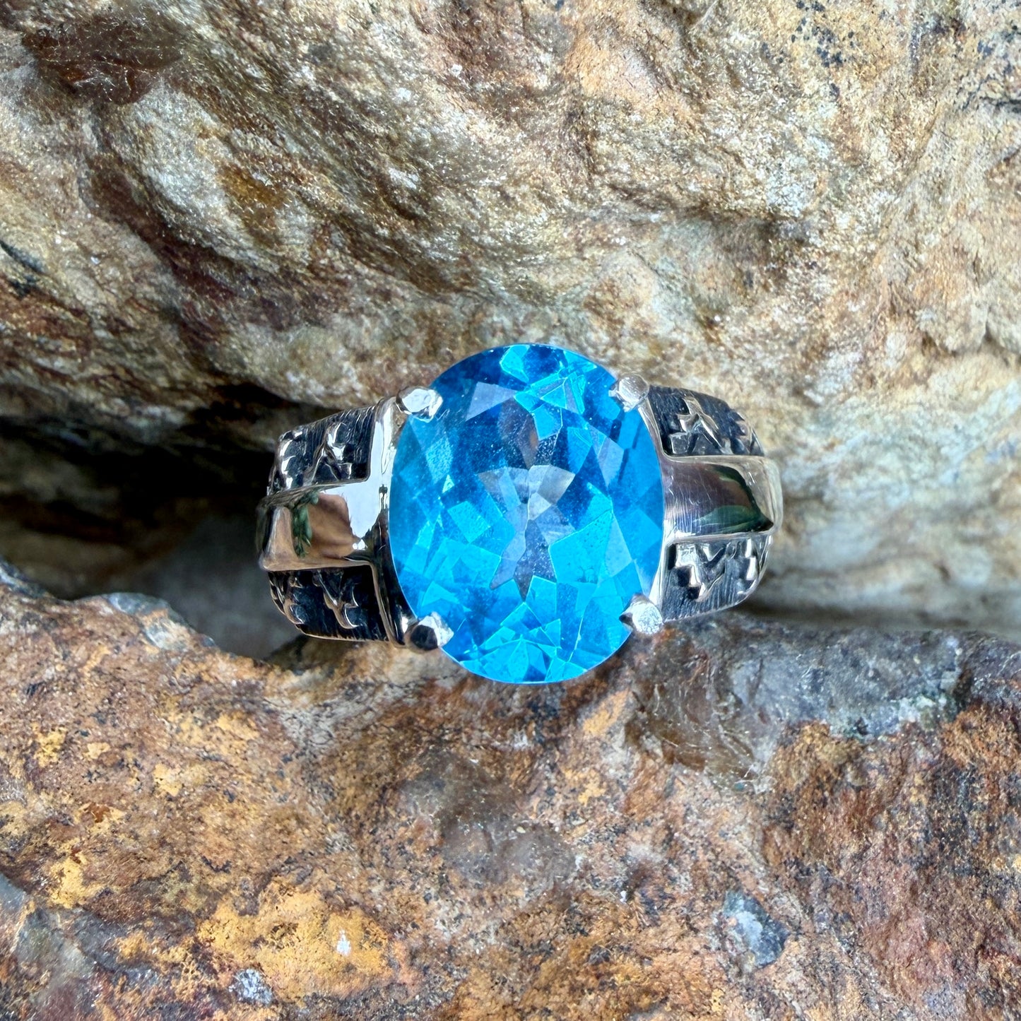 Ring with a blue gemstone and silver band on a rocky background