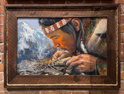 Painting of a person preparing food with mountains in the background, framed and displayed on a brick wall.