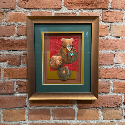 An art piece that contains thinly pressed copper shaped and detailed to represent three traditional Native American ceramic pots. They are placed in the foreground. The background is a dark teal, gold, and red. Framed in a copper-colored frame.