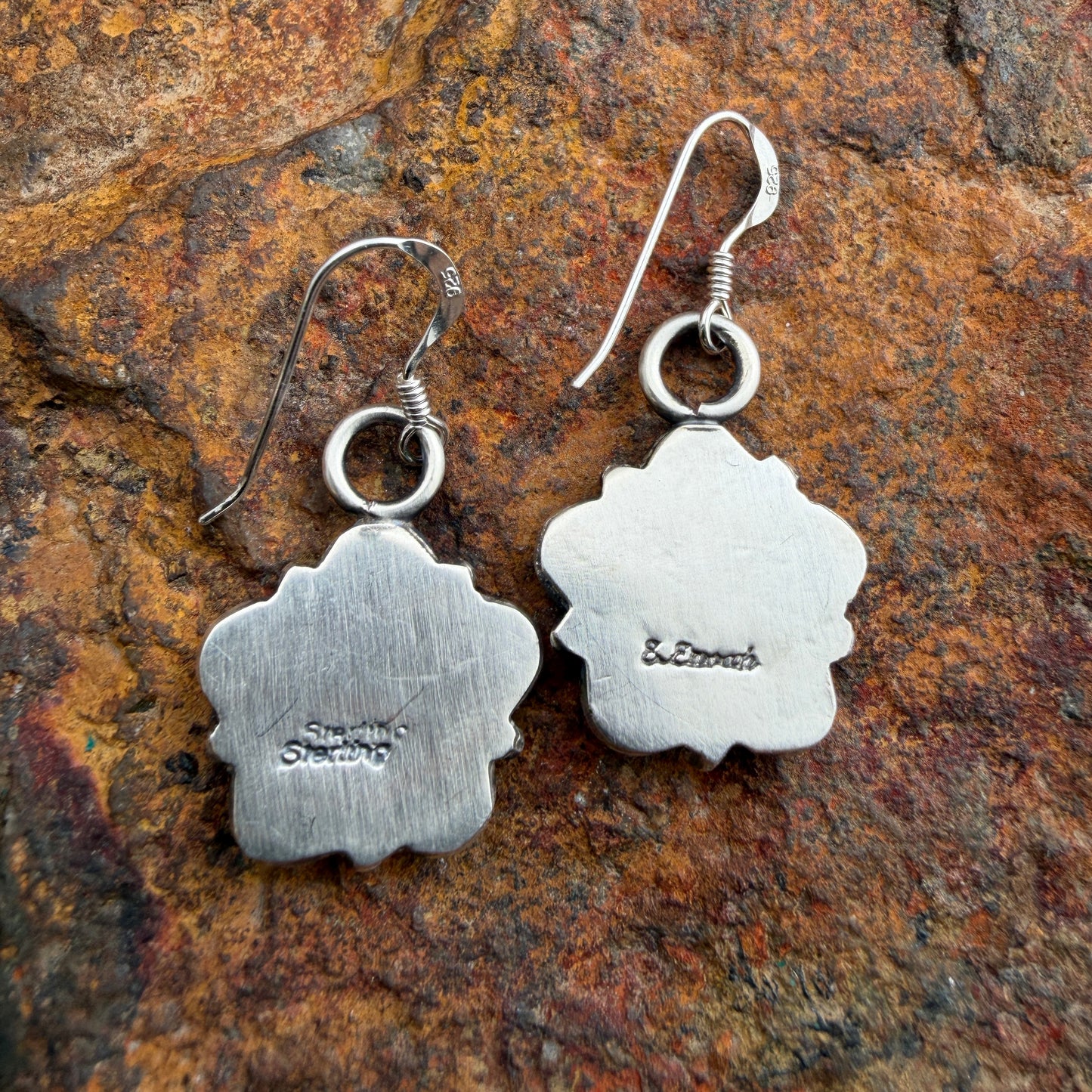 Back of silver floral earrings with stamping on the back. "Sterling" and "E. Enoah"