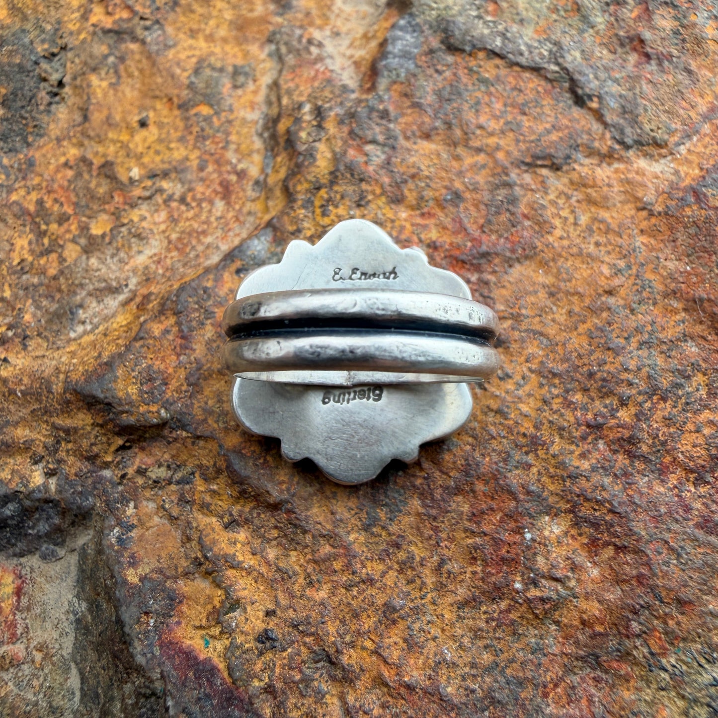 back of a silver ring with stamping on the back. "Sterling" "E. Enoah"