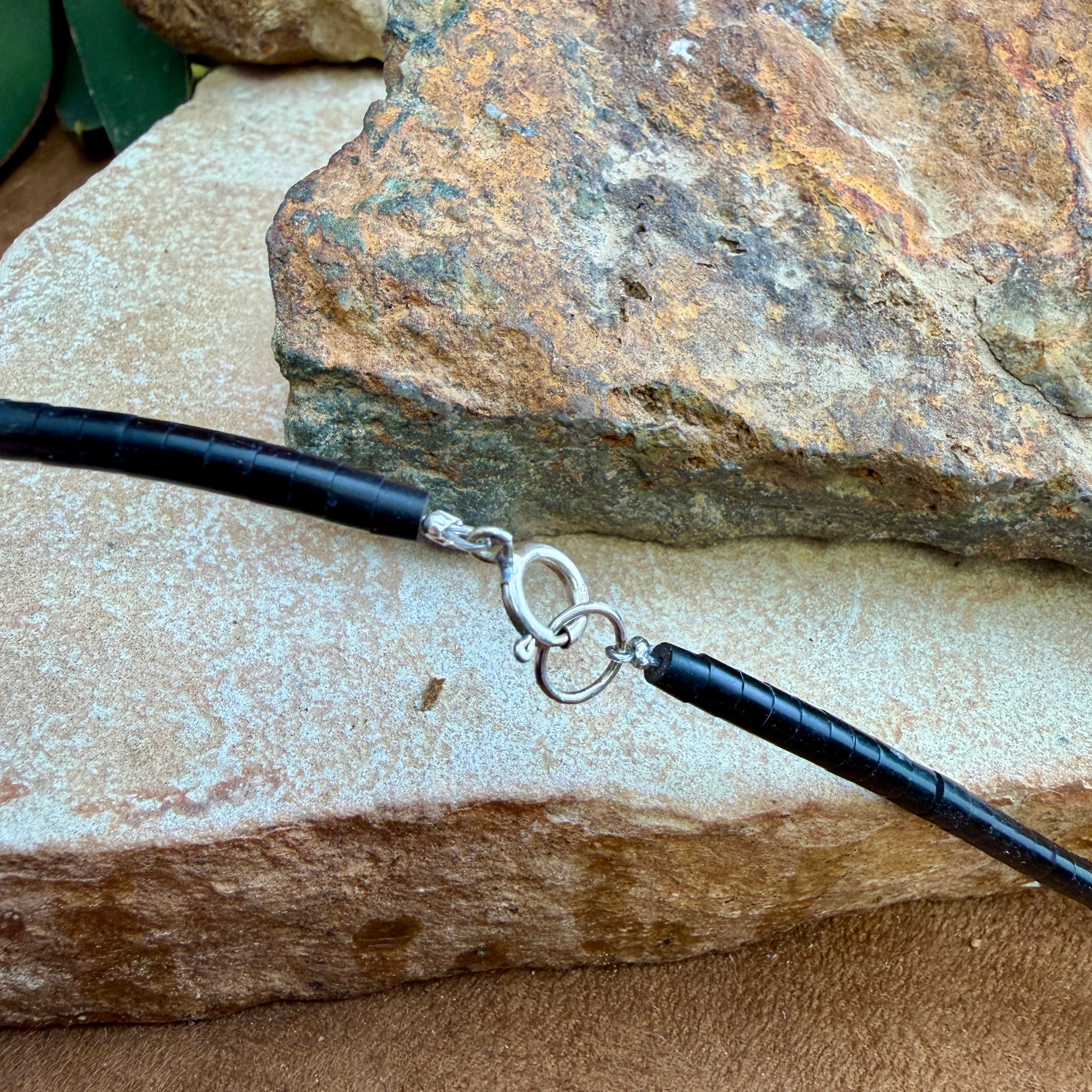 Black beaded end of a necklace with a silver clasp