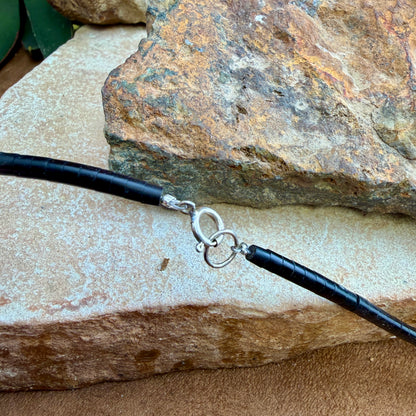 Black beaded end of a necklace with a silver clasp