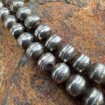 two strands of metallic beads on a textured stone surface