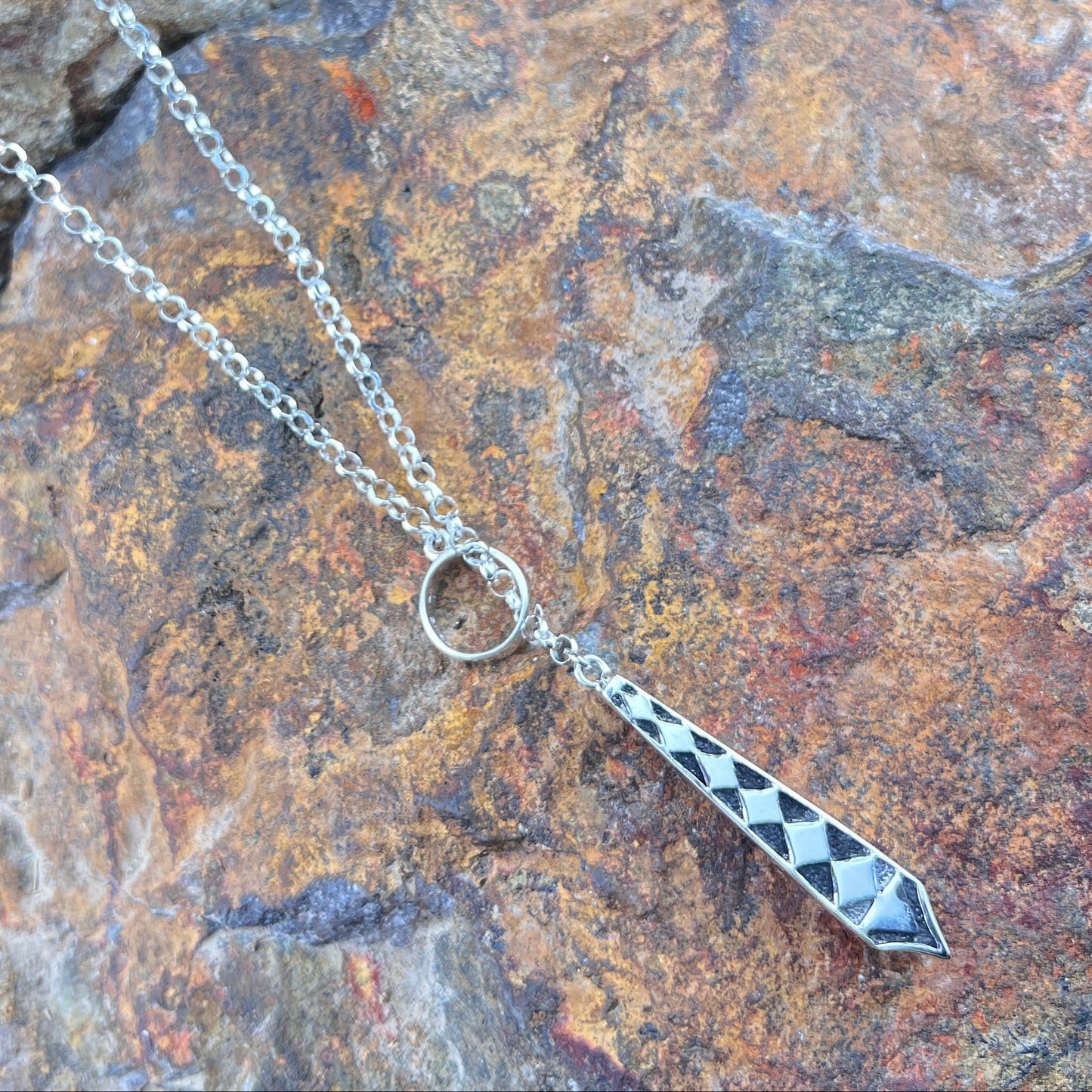 Silver necklace with a pendant on a stone surface