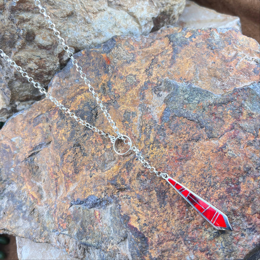 Necklace with a red pendant on a stone surface