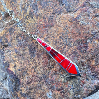 Red and silver pendant on a chain against a stone background
