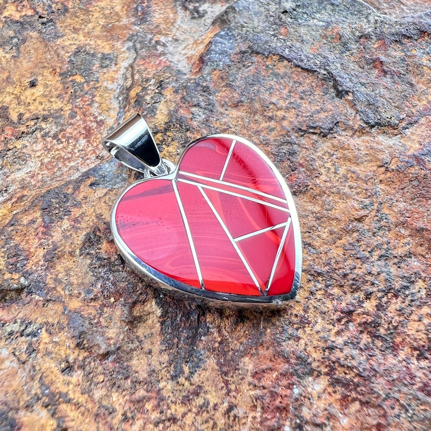 Heart-shaped pendant with geometric design on a stone surface