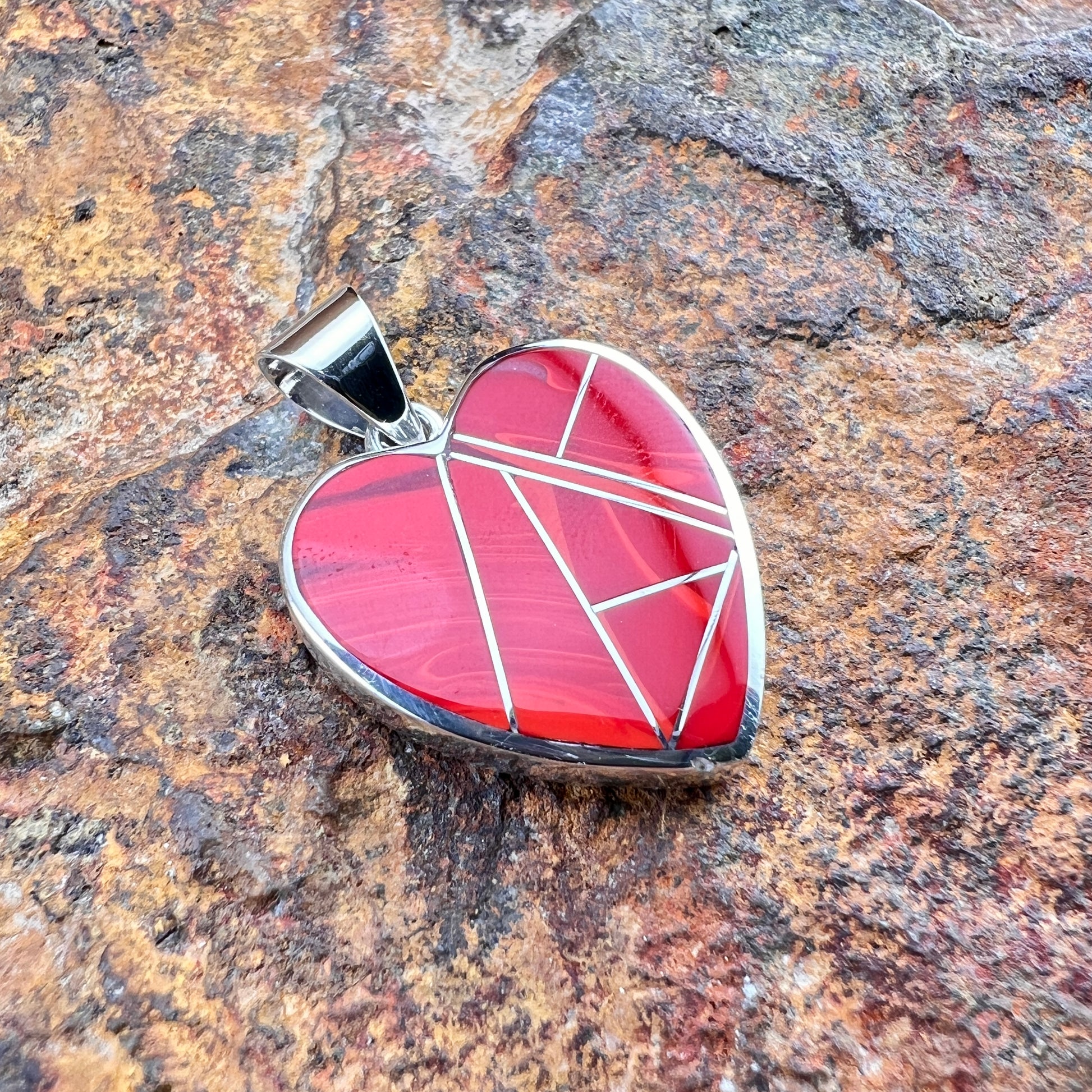 Heart-shaped pendant with geometric design on a stone surface