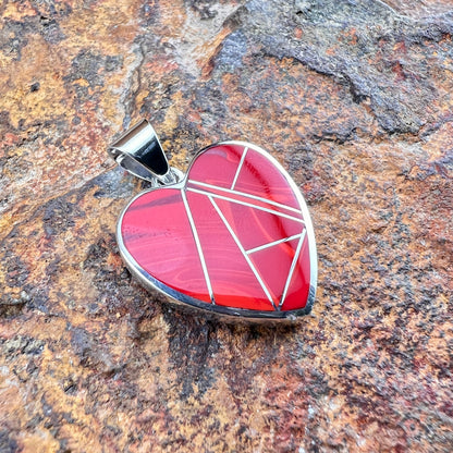 Heart-shaped pendant with geometric design on a stone surface
