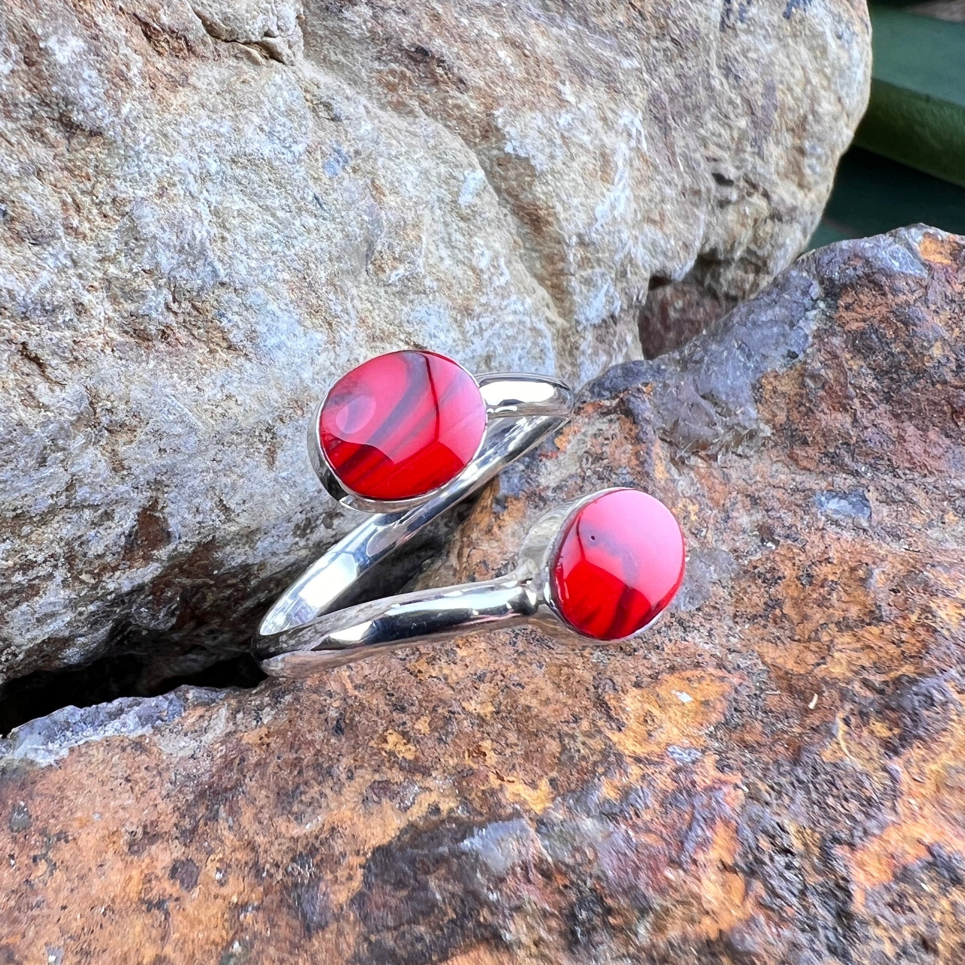 Silver rings with red stones on a stone surface