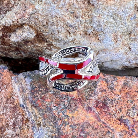 Silver ring with red and blue accents on a rocky surface