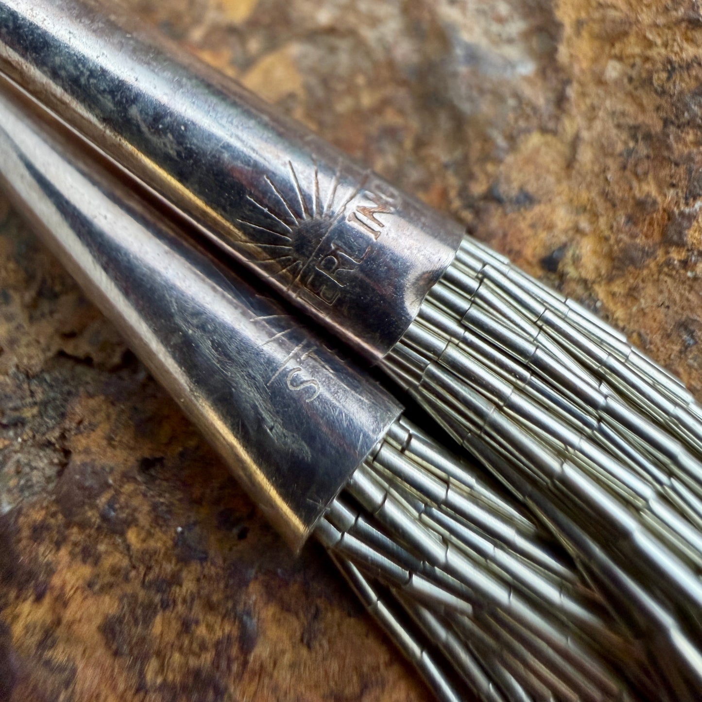 The end caps of the sterling silver multi strand necklace stamped "Sterling" with a sunrise detailing above the wording.