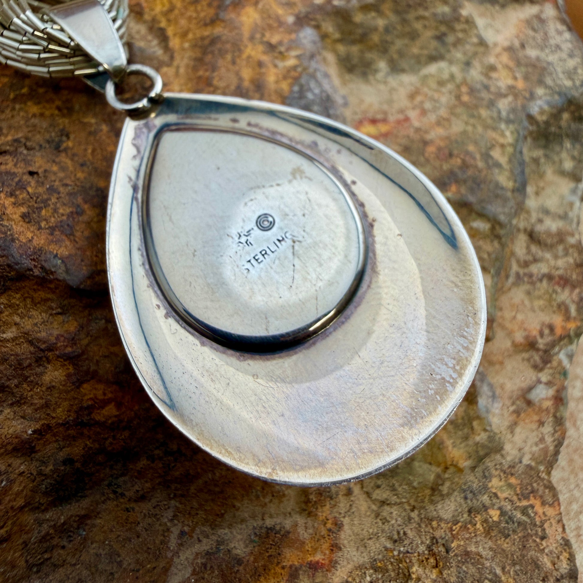 The back of a teardrop pendant, stamped "Sterling" And some other various hallmarks