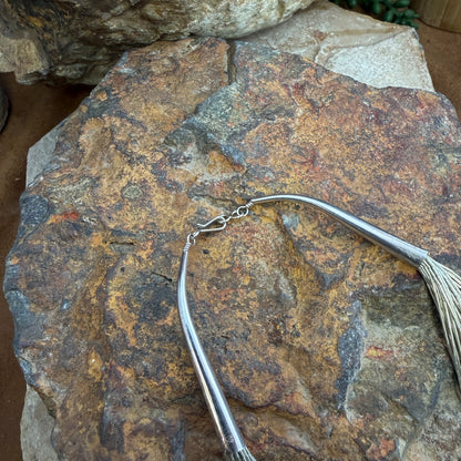 The ends of the multi strand silver necklace, it is a close up of the type of clasp that the necklace features. this type of clasp is hook and eye clasp