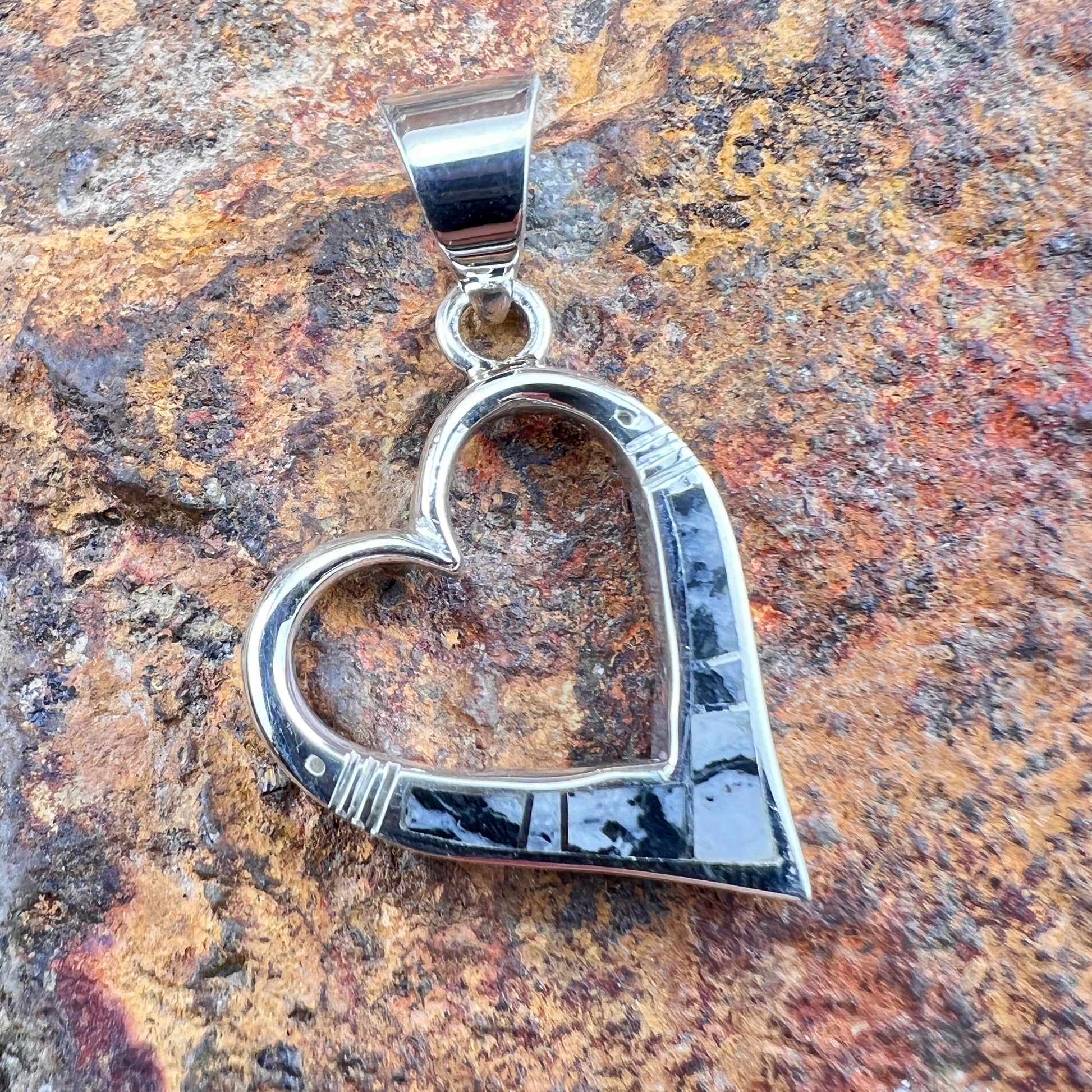 Silver heart-shaped pendant on a textured stone background