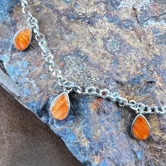 Necklace with orange teardrop pendants on a textured stone surface