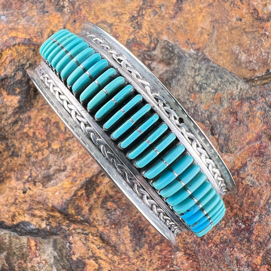 Turquoise stone bracelet with silver band on a stone background
