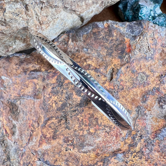 Silver bracelet with intricate design on a textured stone surface