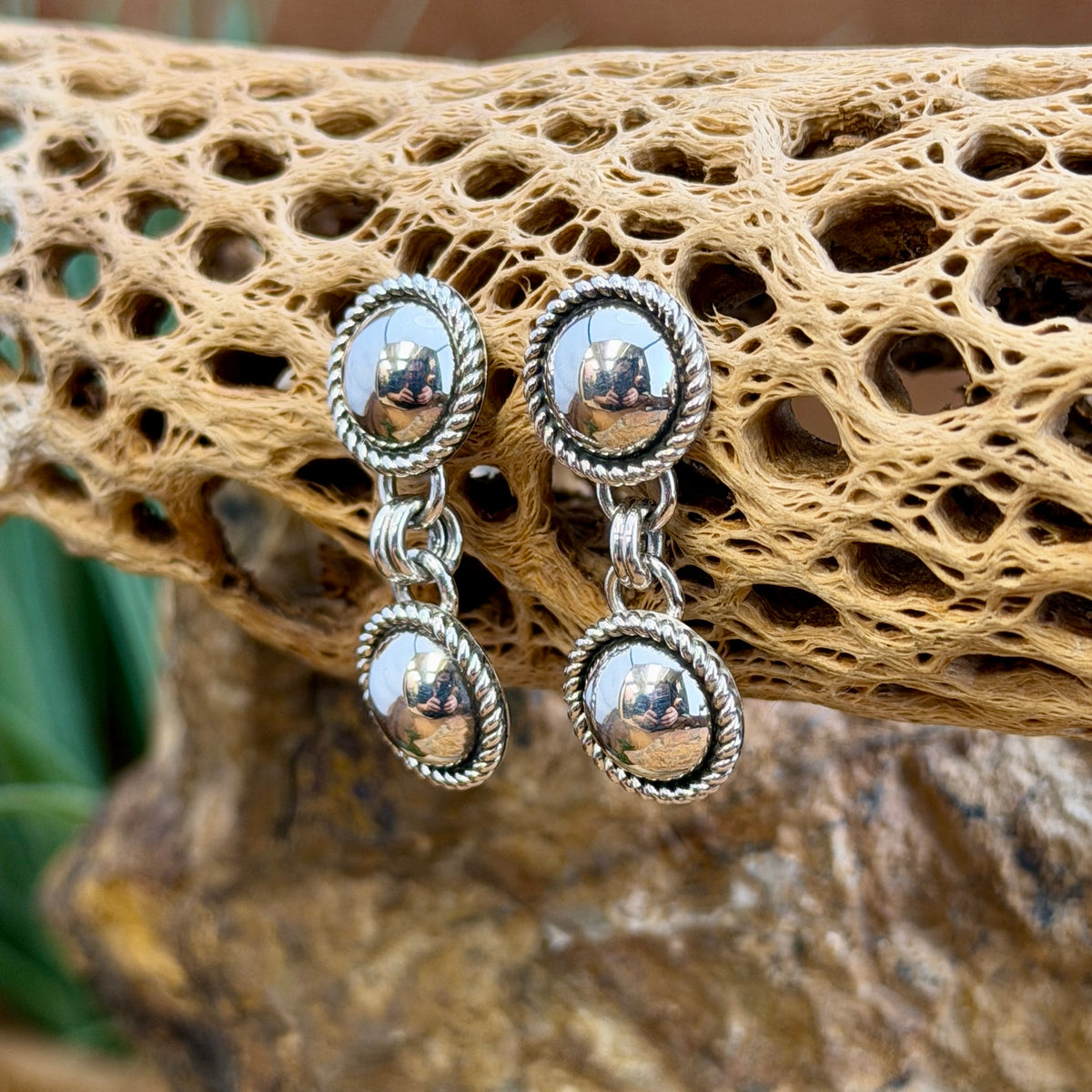 Angled view of polished double dome sterling silver earrings by Artie Yellowhorse