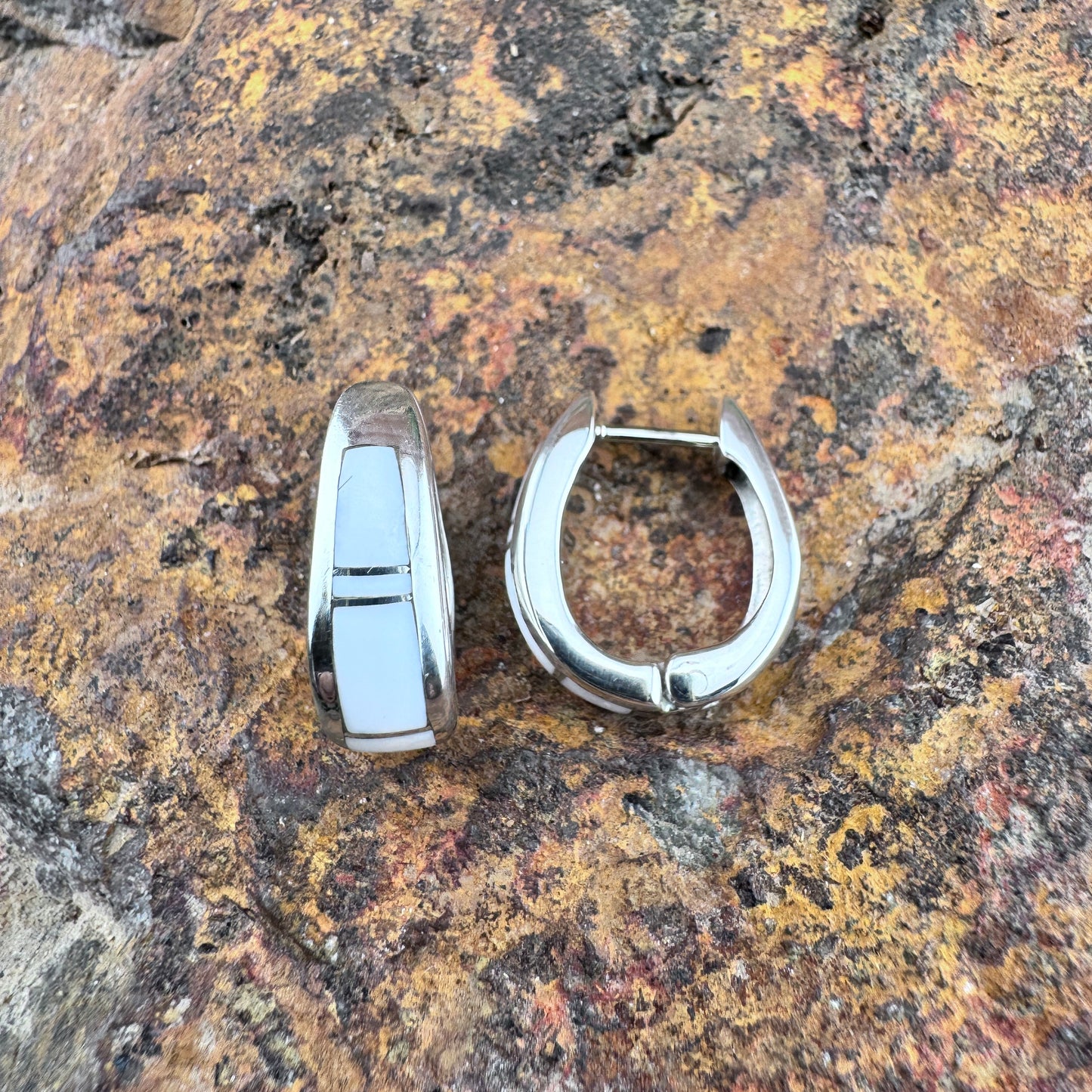 Silver hoop earrings on a textured stone surface