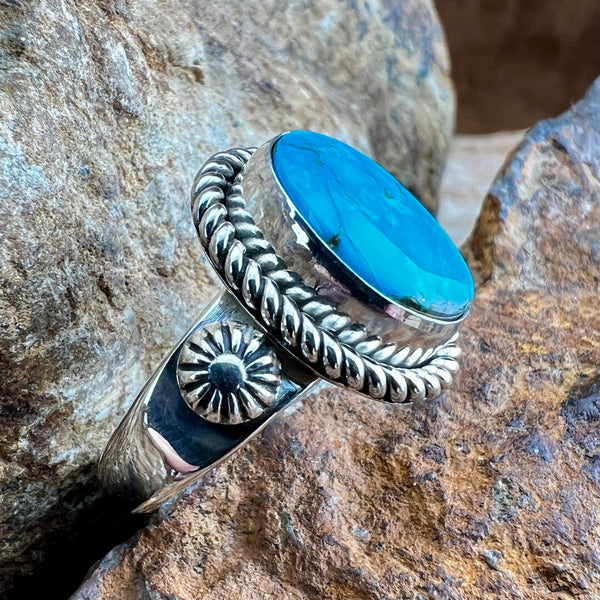 Silver ring with a blue stone on a rocky background