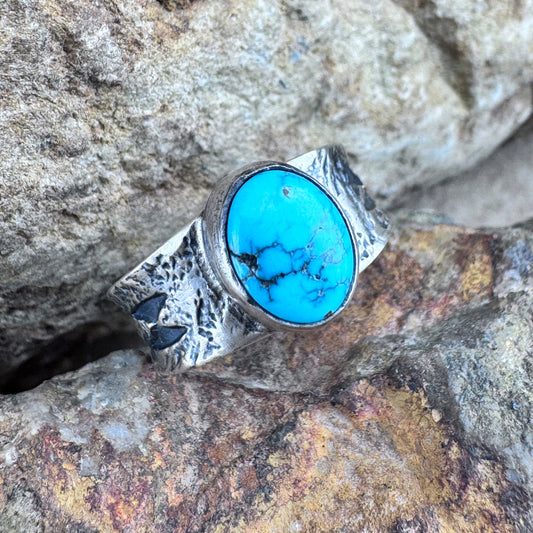 Silver ring with a turquoise stone on a rocky surface