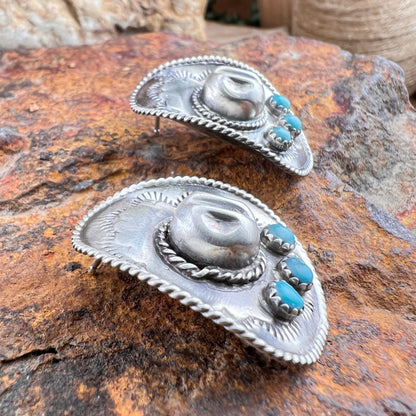 Silver earrings with turquoise stones on a textured stone surface
