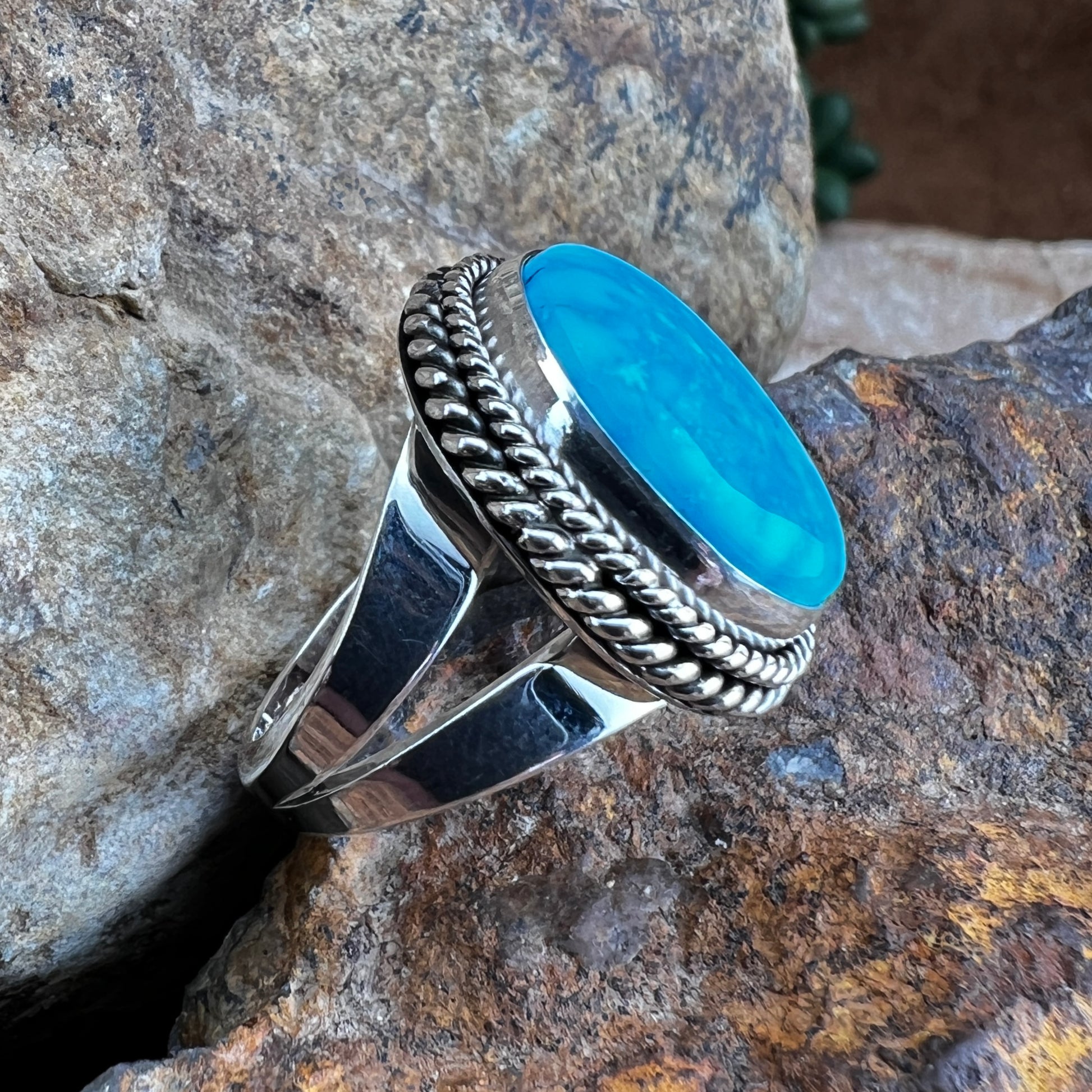 Silver ring with a blue stone on a rocky surface