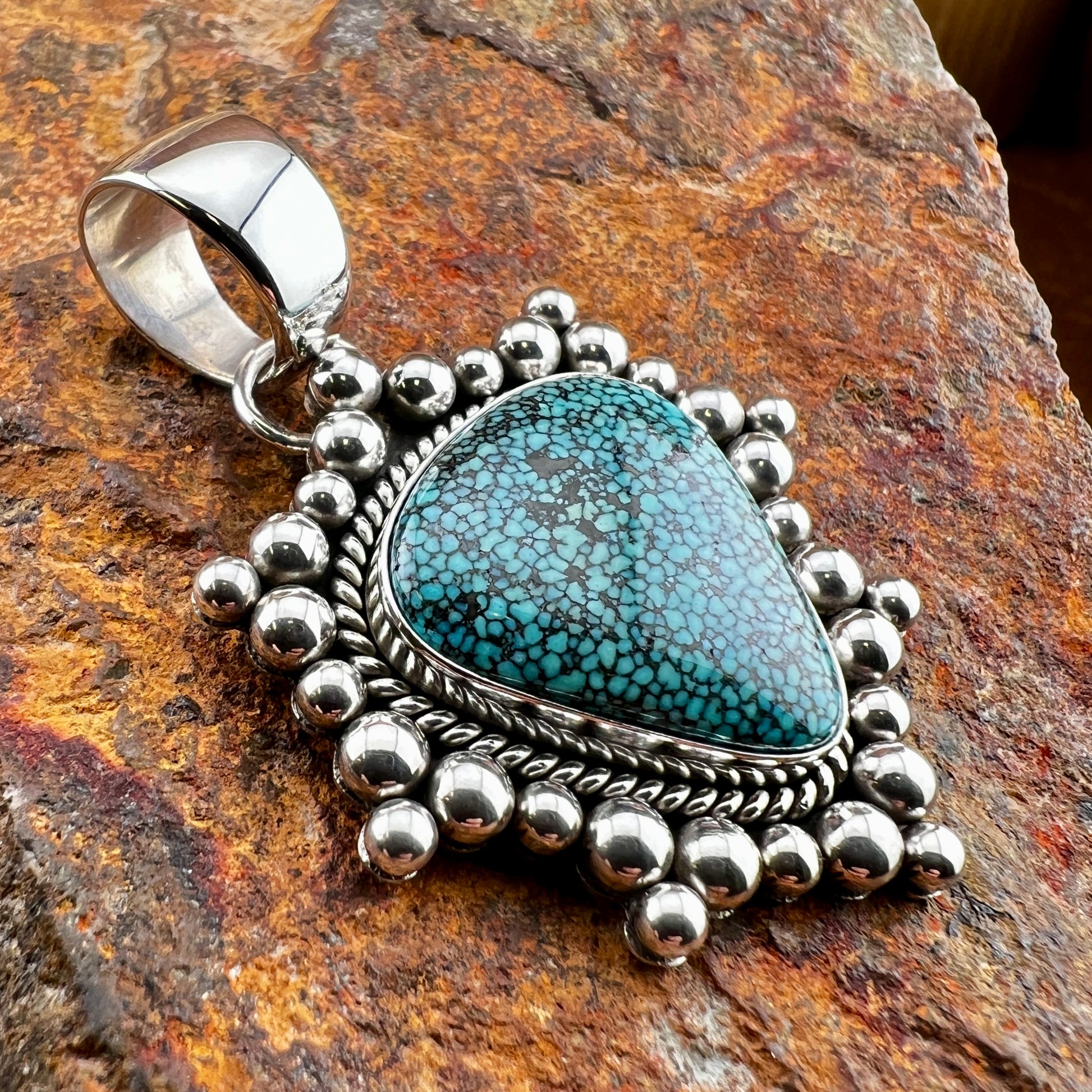 Turquoise pendant with silver beads on a stone background