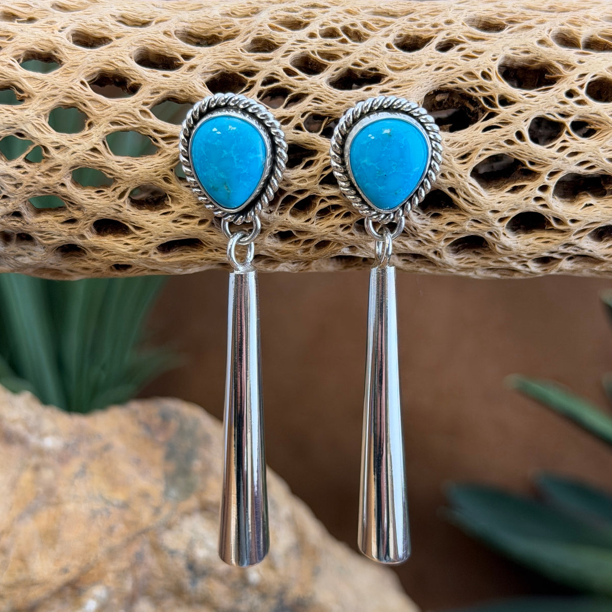 Angled view of Artie Yellowhorse Kingman turquoise long silver drop earrings