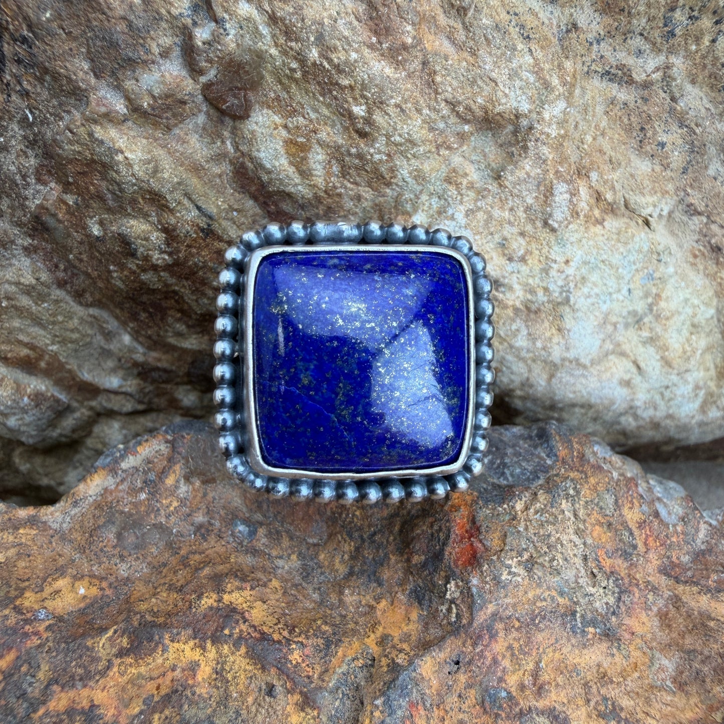 Silver ring with a blue stone on a rocky surface