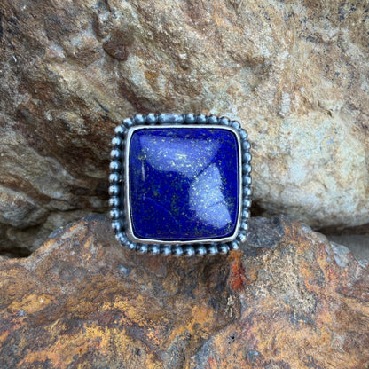 Silver ring with a blue stone on a rocky surface
