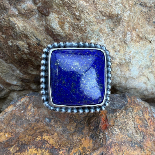 Silver ring with a blue stone on a rocky surface