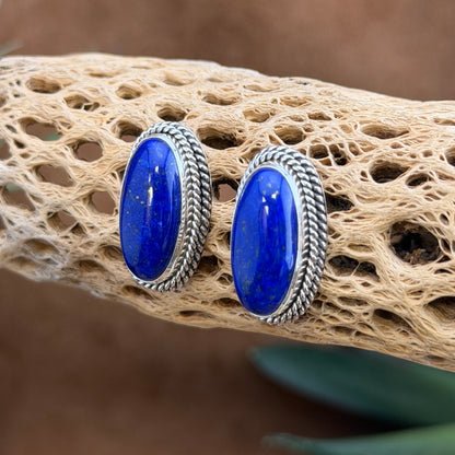 Angled view of sterling silver oval lapis lazuli post earrings with twisted-rope edges