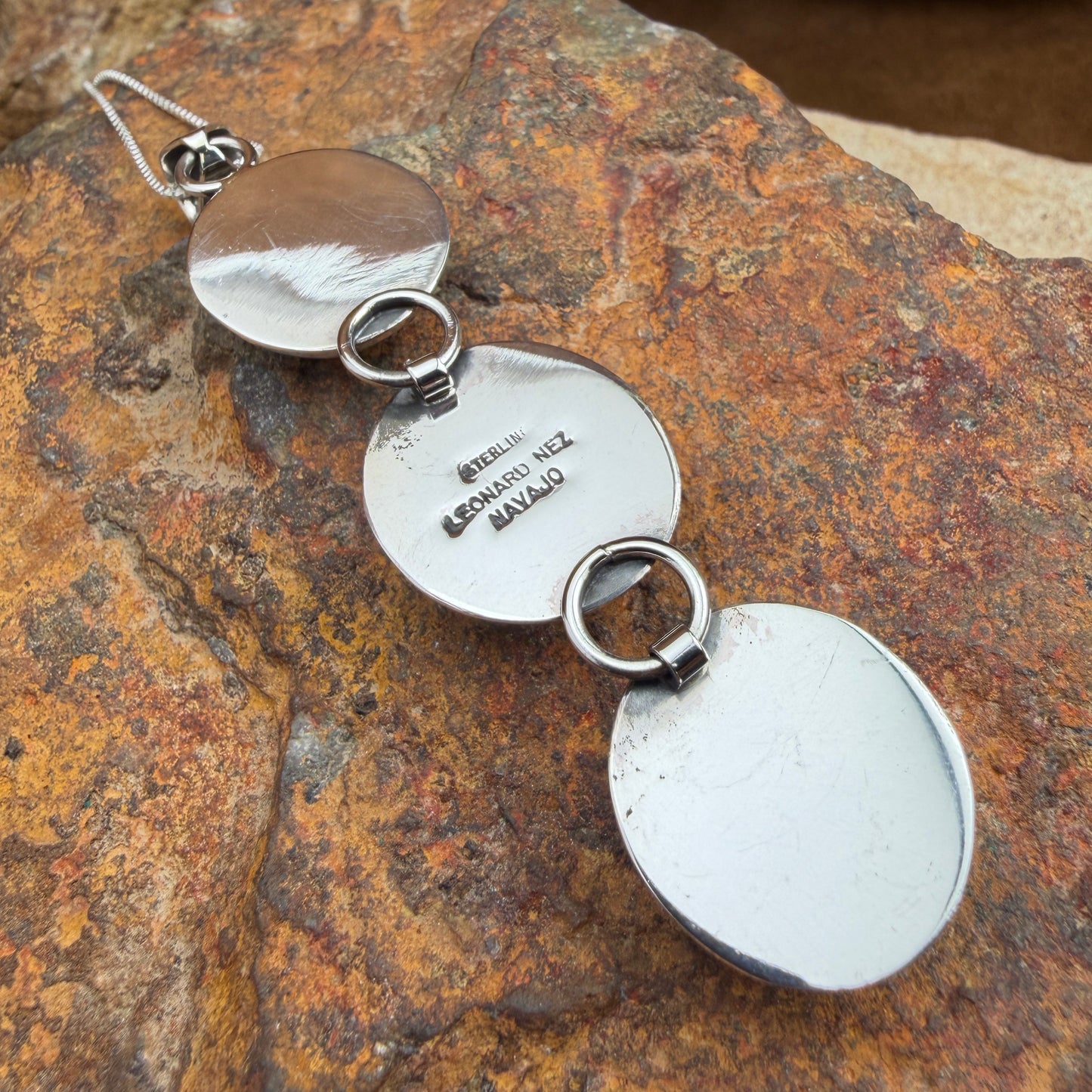 Back of a silver pendent stamped with LEONARD NEZ, STERLING, NAVAJO 